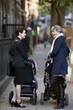 Two mothers pushing their buggies, talking