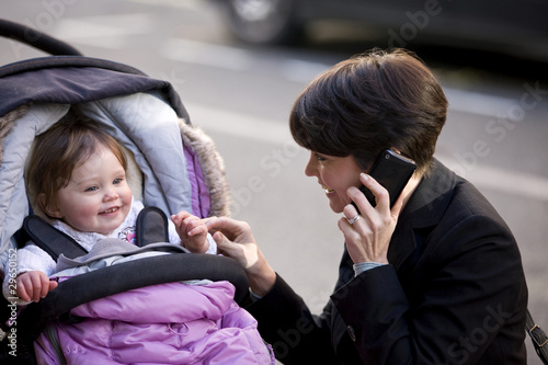 Photo: A mother smiling at her baby, talking on her mobile phone A mother smiling at her baby, talking on her mobile phone