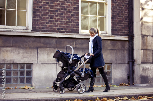 Photo: A mother pushing a double buggy in the street A mother pushing a double buggy in the street