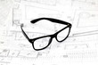 Black glasses on the architectural blueprints in the studio