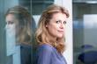 Woman leaning against glass wall in office