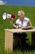 Business Concept Woman Using Megaphone In A Green Field