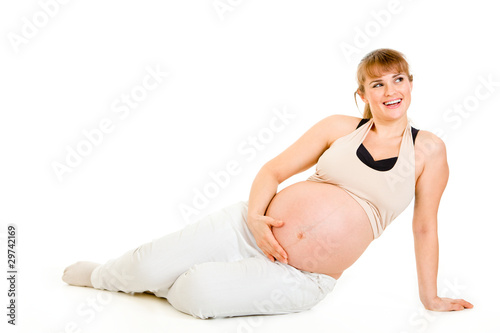 Photo: Dreaming pregnant woman sitting on floor and holding belly Dreaming pregnant woman sitting on floor and holding belly