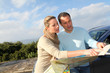 Couple looking at road map on car hood