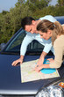 Couple looking at road map on car hood