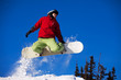 Snowboarder jumping through air with  blue sky in background