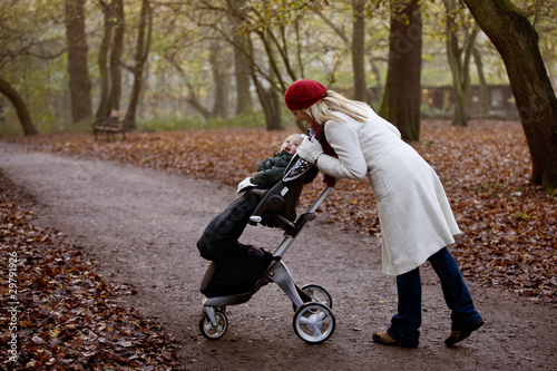 Photo: A young mother checking on her son in a stroller A young mother checking on her son in a stroller
