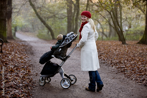 Photo: A young mother pushing a stroller in the park A young mother pushing a stroller in the park