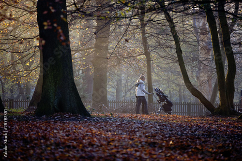 Photo: A young couple pushing a stroller in the park A young couple pushing a stroller in the park