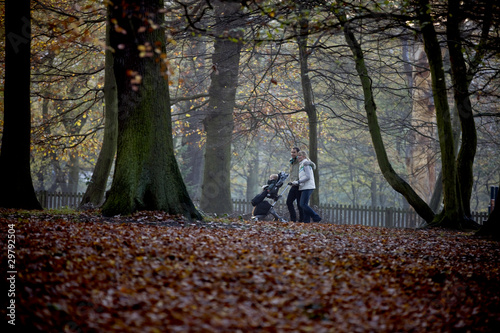 Photo: A young couple pushing a stroller in the park A young couple pushing a stroller in the park