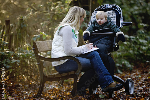 Photo: A young mother sitting on a bench, writing in a journal A young mother sitting on a bench, writing in a journal