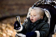 A young boy in a stroller holding an iphone