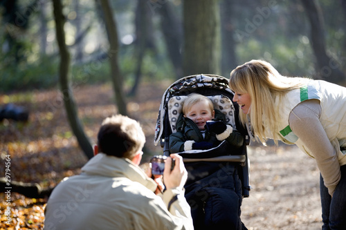 Photo: A father photographing his partner and child in the park A father photographing his partner and child in the park