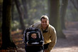 A young father standing with his son in a stroller in the park
