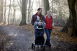 A young couple pushing a stroller in the park, smiling