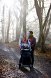 A young couple standing with a stroller in the park, talking