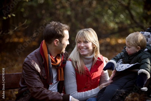 Photo: A young couple on a bench, next to their son in a stroller A young couple on a bench, next to their son in a stroller