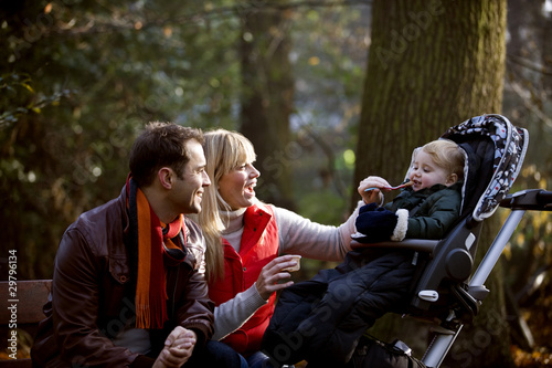 Photo: A young couple feeding their son in the park A young couple feeding their son in the park
