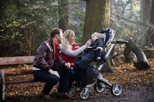Photo: A young couple feeding their son in the park A young couple feeding their son in the park