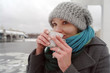 The young white frozen girl drinks hot tea in the winter