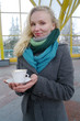 The young white girl has control over a cup with tea and smiles