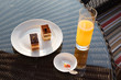 Glass of orange juice and snack on rattan table