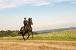 Photo: Rider rides at a gallop across the field. Rider rides at a gallop across the field.