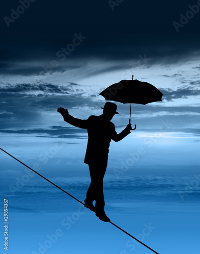 Photo: Man walking tightrope silhouette Man walking tightrope silhouette