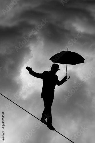 Photo: Tightrope Silhouette against black cloud Tightrope Silhouette against black cloud