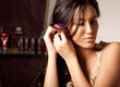 Portrait of young brunette woman fixing flower in curly hair