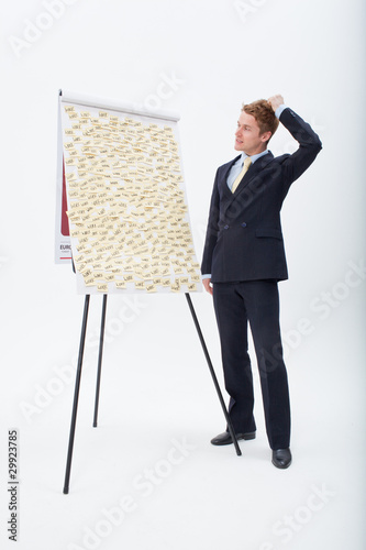 Photo: Confused businessman standing at flipchart with abundance of post-its Confused businessman standing at flipchart with abundance of post-its