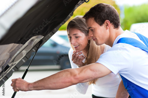 Foto: Frau spricht mit Automechaniker in Werkstatt Frau spricht mit Automechaniker in Werkstatt