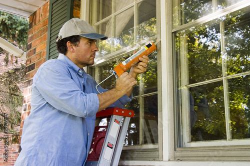 Photo: Man Caulking Window Man Caulking Window