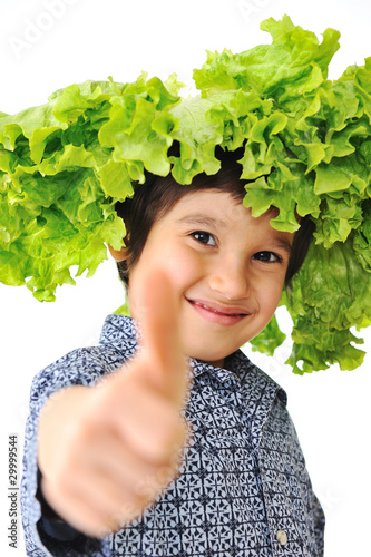 Photo: Kid with salad as a hat or wig on his head, thumb up, concept Kid with salad as a hat or wig on his head, thumb up, concept