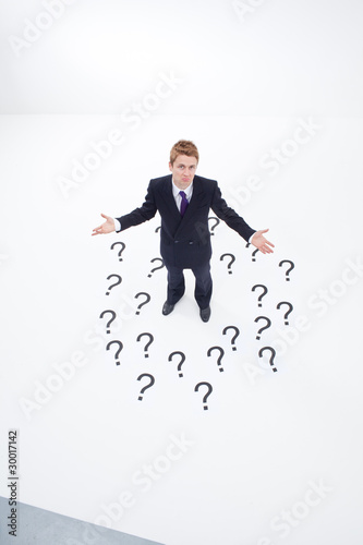 Photo: Confused businessman surrounded by question marks Confused businessman surrounded by question marks