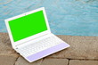 Laptop with green screen near to swimming pool