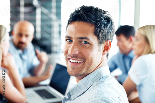 Photo: Successful businessman in meeting with colleagues at back Successful businessman in meeting with colleagues at back