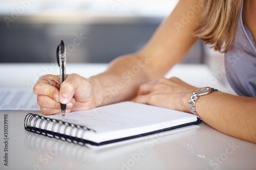 Photo: Woman's hand with pen writing down notes Woman's hand with pen writing down notes