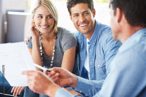 Foto: Young couple discussing investment plans with advisor Young couple discussing investment plans with advisor