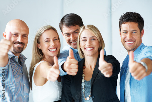 Photo: Business approval - Young colleagues with thumbs up sign Business approval - Young colleagues with thumbs up sign