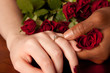 Newly engaged couple showing off ring with red roses around