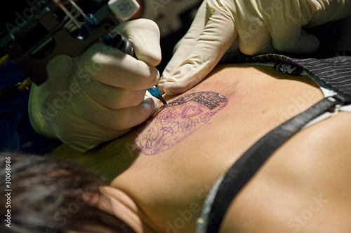 Photo: Tattoo artist at work with a young girl. Tattoo artist at work with a young girl.