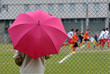 Parent observes young players in the rain Parent observes young players in the rain