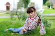 Adorable little girl in colorful clothes sits on grass Adorable little girl in colorful clothes sits on grass