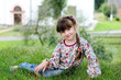 Adorable little girl in colorful clothes sits on grass Adorable little girl in colorful clothes sits on grass