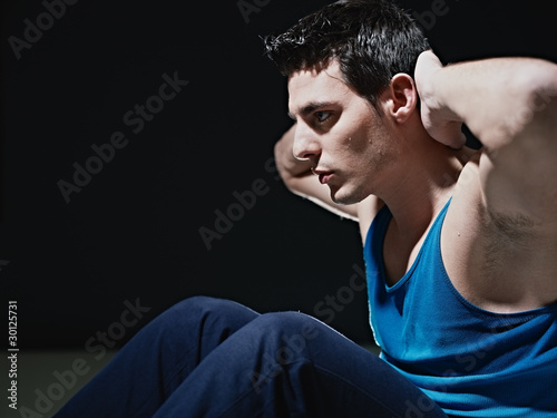 Photo: man doing series of sit-ups on black background man doing series of sit-ups on black background
