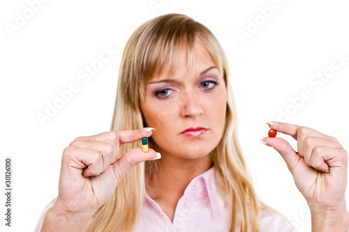 Photo: junge frau schaut nachdenklich auf zwei tabletten junge frau schaut nachdenklich auf zwei tabletten