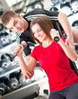 Trainer helps young girl with dumbbells in fitness club Trainer helps young girl with dumbbells in fitness club