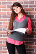 Smiling young business woman with document over brickwall