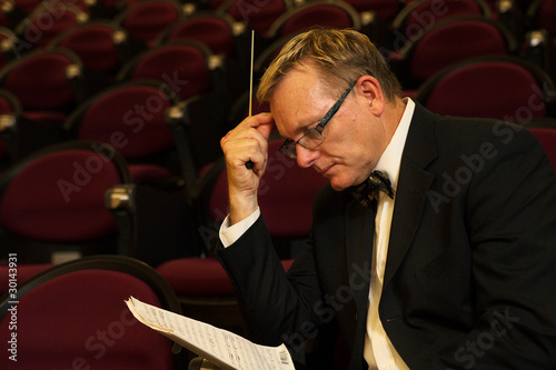 Photo: Male symphony conductor studying his music score Male symphony conductor studying his music score